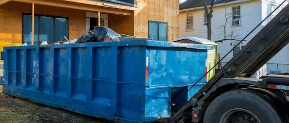 Reliable dumpster rental crew loading debris into sturdy roll-off dumpster safely.