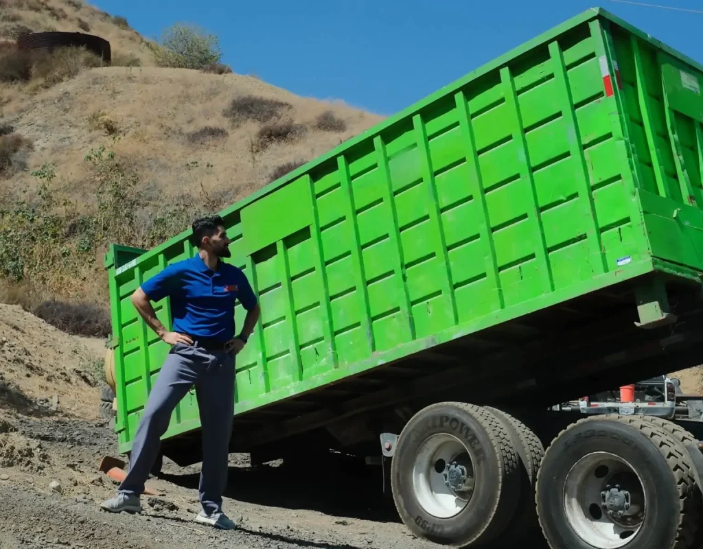 Worker loading debris into Zippy Dumpster container in San Bernardino County, CA