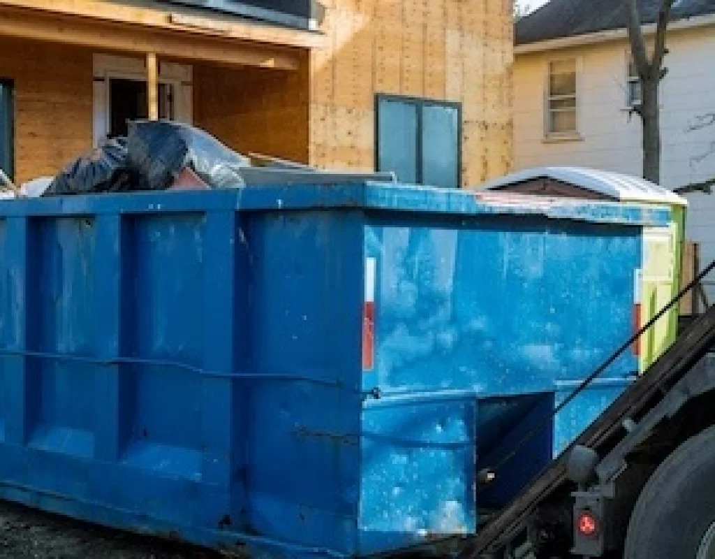 Reliable dumpster rental crew loading debris into sturdy roll-off dumpster safely.